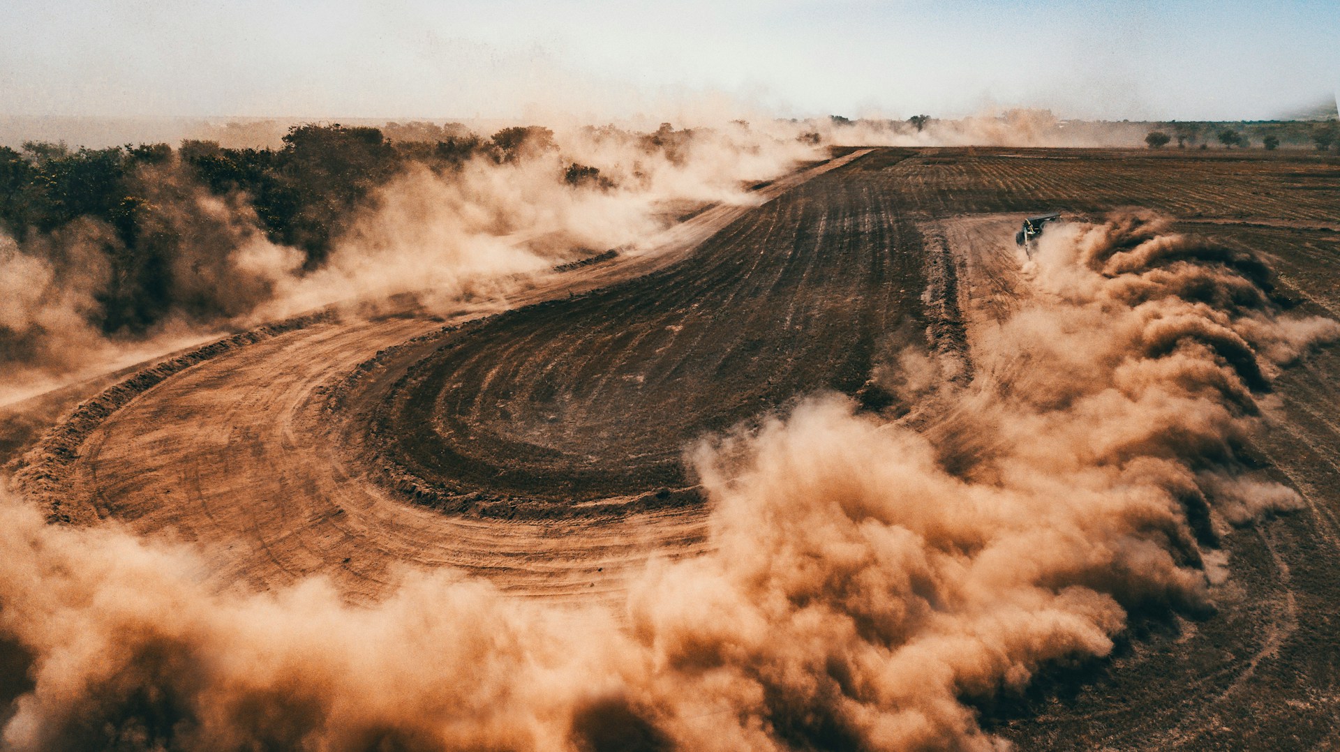 Off-road machine driving through a dusty trail